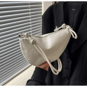 Detail of white half-moon shoulder bag featuring knotted strap and silver hardware