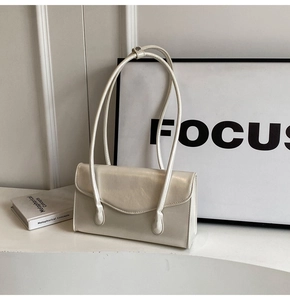 Detail of cream rectangular underarm bag with glossy leather texture and double thin straps