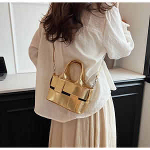 Detail of a golden metallic woven mini handbag with silver twist lock and slim strap