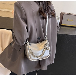 Détail d'un sac bandoulière argenté à motif crocodile avec poignée chaîne sur un costume