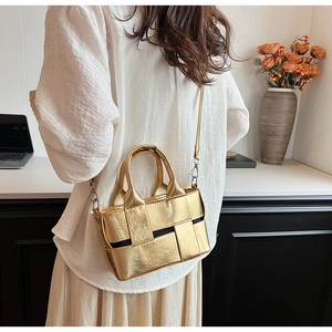Golden woven mini tote bag shown with adjustable shoulder strap on a model with white shirt