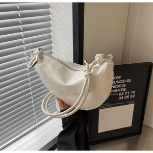 Close-up of a white dumpling-style shoulder bag with a unique knotted strap and metal end caps
