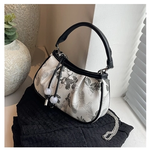 Detailed view of ink-wash embroidery and moon-shaped silhouette on this elegant handbag