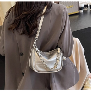 Sac à bandoulière argenté en demi-lune avec chaîne métallique sur une veste de blazer