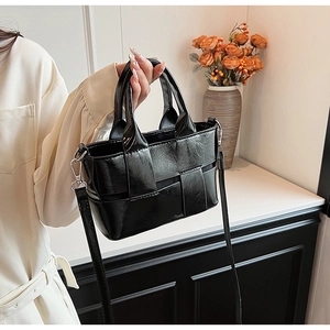 Detail of black woven leather handbag with adjustable strap and textured surface