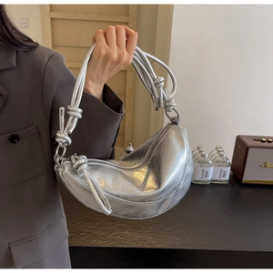 Detail of silver half-moon handbag featuring a unique thick rope knot handle design