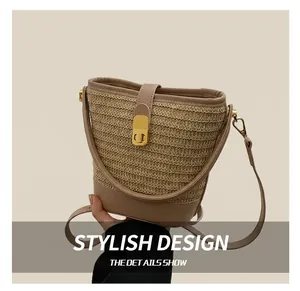 Detail of woven straw bucket bag with khaki leather trim and golden metal turn-lock