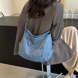 Retro blue denim style large tote bag with zipper pockets shown on a stylish shoulder