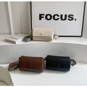 Detailed view of three mini cylinder crossbody bags with wide patterned straps on white steps