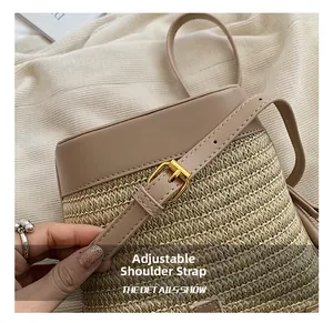Detailed macro view of the adjustable leather strap and gold buckle on a straw bucket bag