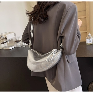 Detail of silver metallic crescent bag with retro crinkle texture and knotted shoulder strap