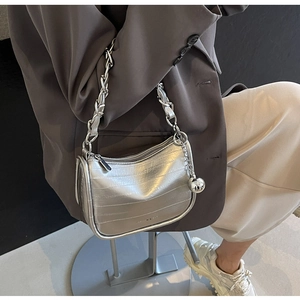 Sac bandoulière argenté avec texture métallique, chaîne et grand pendentif sphérique
