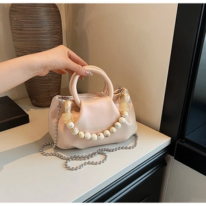 Détail du sac nuage plissé rose avec perles jaunes décoratives et chaîne en métal argenté