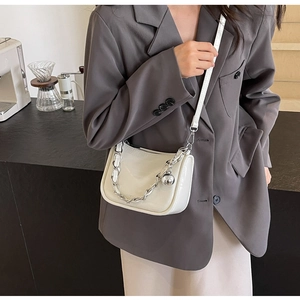 Sac à bandoulière blanc motif croco avec chaîne argentée et breloque sphérique sur modèle
