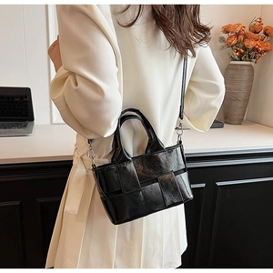 Model showing a black woven texture handbag with dual handles and detachable shoulder strap