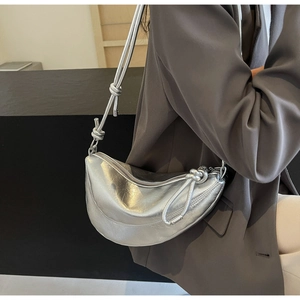 Detail of silver metallic crescent bag featuring unique knot design and textured finish