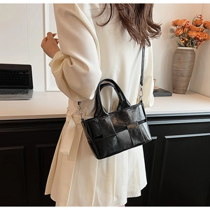 Detail of black woven leather handbag showing upper body fit on a model in a cozy office