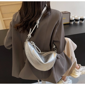 Silver crescent hobo bag with metallic pleats and knot detail worn by a model