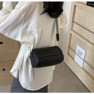 Close-up of black lychee texture cylinder bag with checkered wide shoulder strap