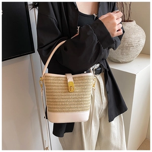 Detailed view of straw bucket bag with golden twist lock and beige leather texture