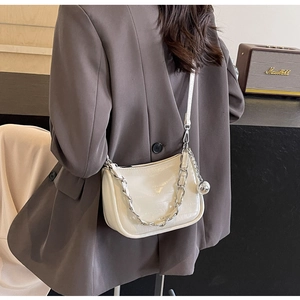 Détail du sac bandoulière blanc ivoire à motif crocodile avec breloque boule argentée