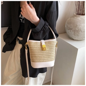 Detail of woven straw bucket bag with white leather trim and gold twist lock closure