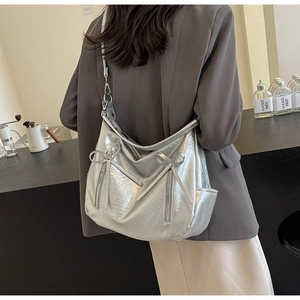 Detail of silver bucket bag with litchi texture and cute bow accents on a hobo bag