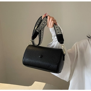 Detail view of black pebble-textured crossbody bag with vintage geometric woven wide strap