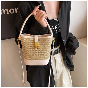 Detail of woven straw bucket bag showing leather base and gold twist lock closure