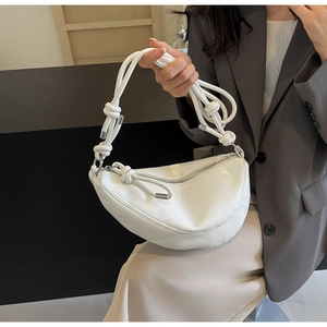 Close-up of white crescent bag showing knotted shoulder strap and silver metal buckle