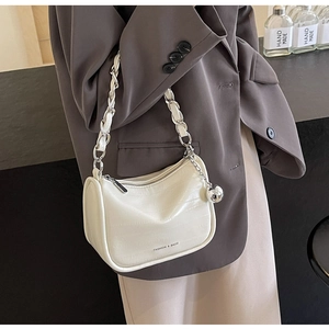 Détail du sac blanc à texture crocodile avec chaîne argentée et breloque sur un mannequin