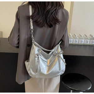 Detail view of silver bucket bag featuring metallic crinkled texture and bow accents
