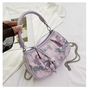 Detail of lavender floral embroidery on a pleated textured fabric small square handbag