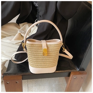 Detail of woven straw bucket bag with white leather trim and gold metal clasp