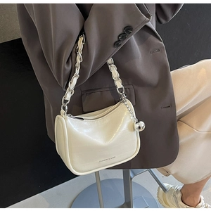 Détail de sac blanc à texture crocodile avec chaîne argentée et breloque sphérique