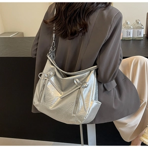 Detail of silver pleated bucket bag with metallic bows and functional side pocket