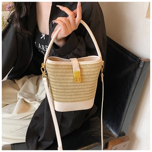 Close-up of woven straw bucket bag showing leather stitching and gold metal buckle