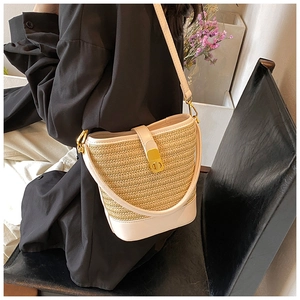 Detailed view of the woven straw bucket bag with white leather trim and gold CD clasp