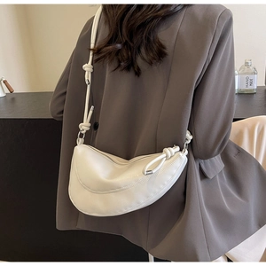 Detailed view of a white crescent moon bag with knotted shoulder strap and silver zipper