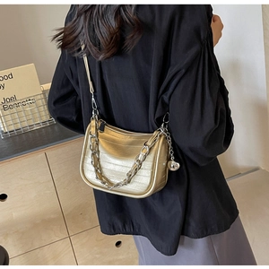 Détail du sac demi-lune doré champagne à motif crocodile avec chaîne argentée et boule