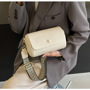 Detail of off-white lychee texture leather bag with geometric wide strap on a model