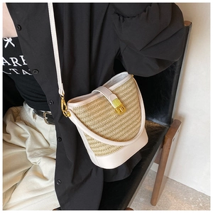 Detail of woven straw bucket bag with cream leather trim and gold D-ring buckle