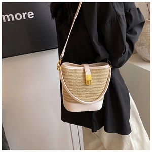 Detail of hand-woven straw bucket bag with cream leather trim and gold metal twist lock