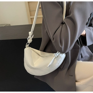 Chic white crescent moon shoulder bag featuring a knotted strap detail and silver zipper