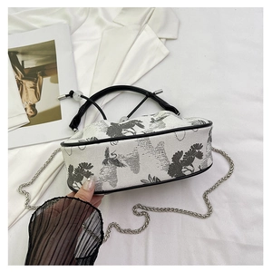 Detail of Chinese crane embroidery and silver chain strap on a white crossbody bag
