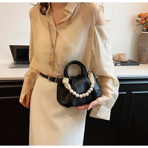 Détail d'un sac nuage plissé noir avec poignée en perles et fine bandoulière en chaîne