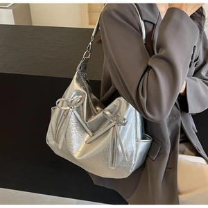 Close-up of a silver bucket bag with bow detail and lychee texture on shoulder strap