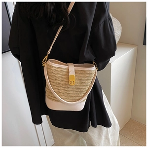 Detail of woven straw bucket bag with pink leather trim and golden twist-lock closure