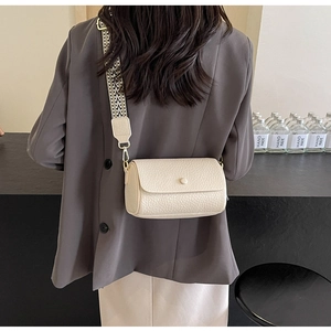 Detailed back view of a beige cylinder crossbody bag with a wide geometric woven strap