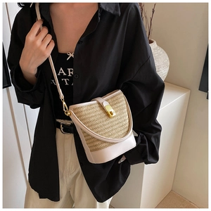 Detail of woven straw bucket bag with cream leather trim and gold twist-lock closure